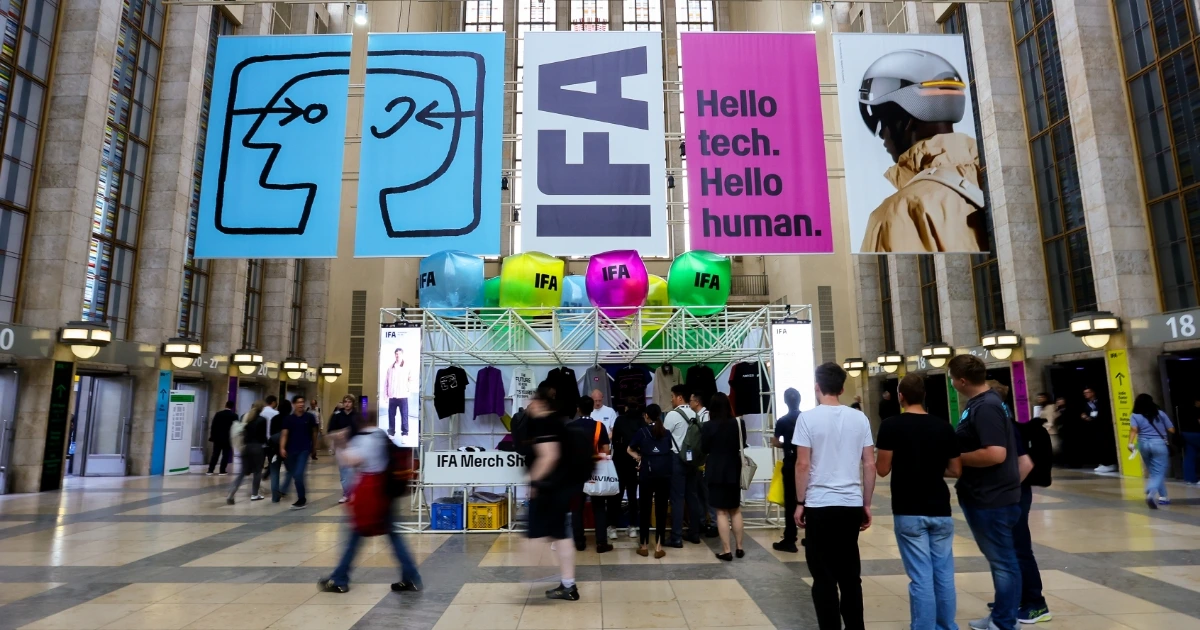 Messeeingang der IFA Berlin 2026 mit bunten Fahnen, Besuchern und Merch Shop
